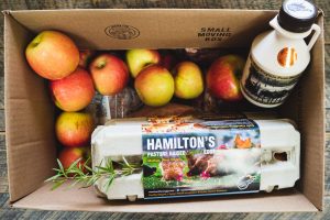 Apples, eggs, maple syrup, and rosemary in a box