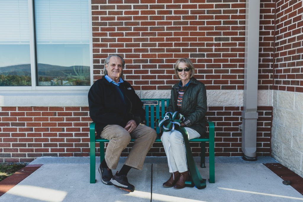 A couple sits on a green metal bench.