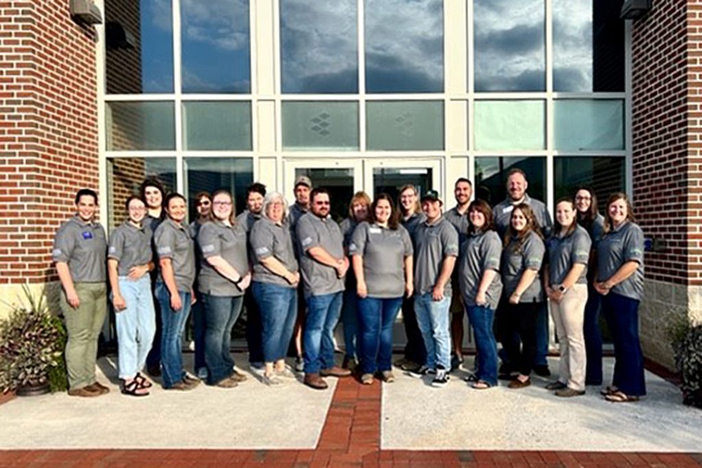 a group of teachers standing in front of entrance to college