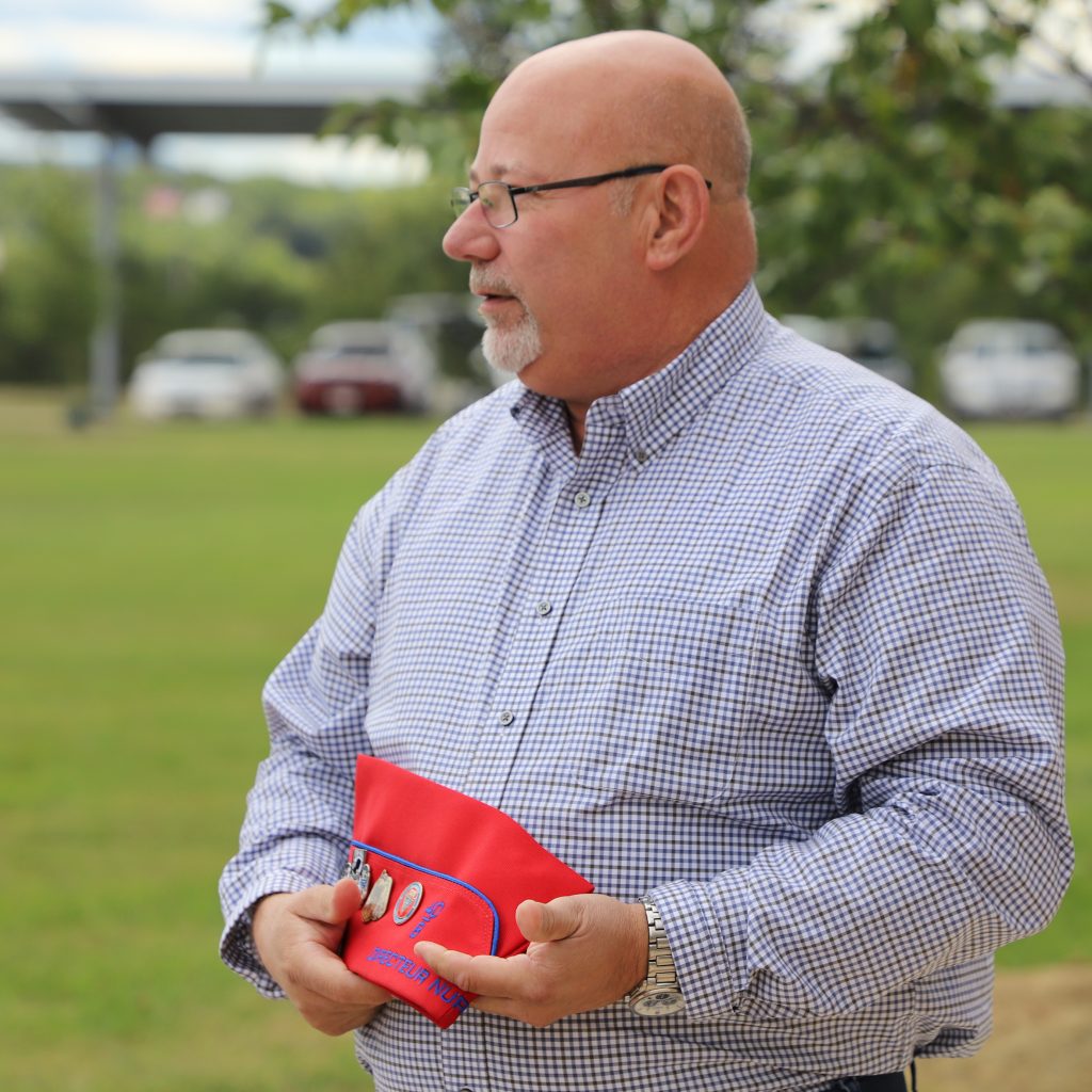 A man holds his hat. The insignias and text on the hat describe his position in the 40 & 8 Veterans Organization.