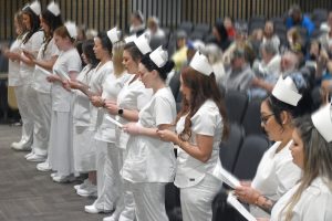 Members of the 2022 Nursing Cohort at Eastern West Virginia Community and Technical College stand at the front of the auditorium and read the Nightingale Pledge at their Pinning Ceremony in May 2022.