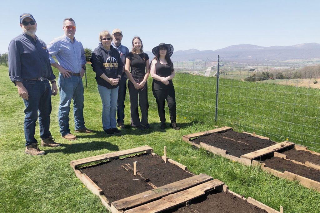 Pollinator garden seminar participants stand behind the new raised-bed pollinator garden that was planted on Eastern's campus.