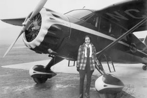 A young Black woman standing in front of a single wing, propeller-driven small airplane. The photo is undated, but is probably from the 1940s.