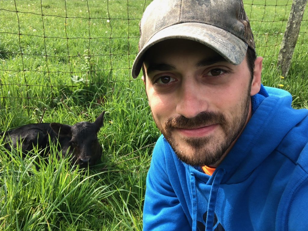 Shayne Turner crouches in a field with a calf.