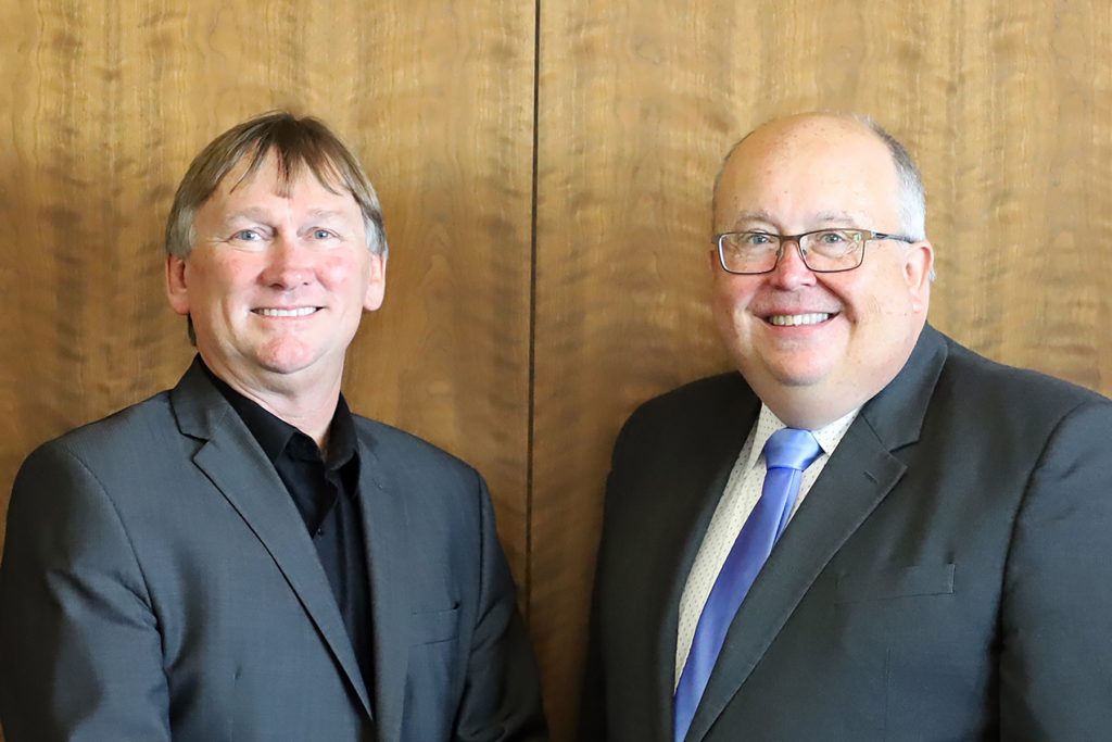 Two professionally dressed men smile for a portrait.